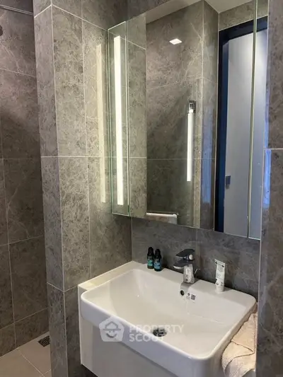 Modern bathroom with sleek sink and illuminated mirror in luxury apartment.