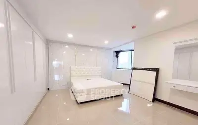 Spacious modern bedroom with elegant white decor and ample natural light.