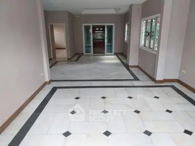 Spacious open-plan living area with elegant tiled flooring and large windows for natural light.