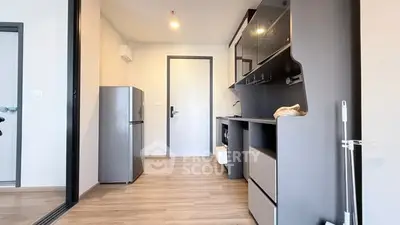 Modern kitchen with sleek cabinetry and compact fridge in a stylish apartment.