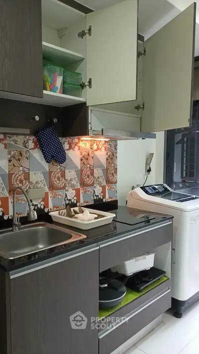 Modern kitchen with stylish backsplash and washing machine, featuring open cabinets and sleek design.