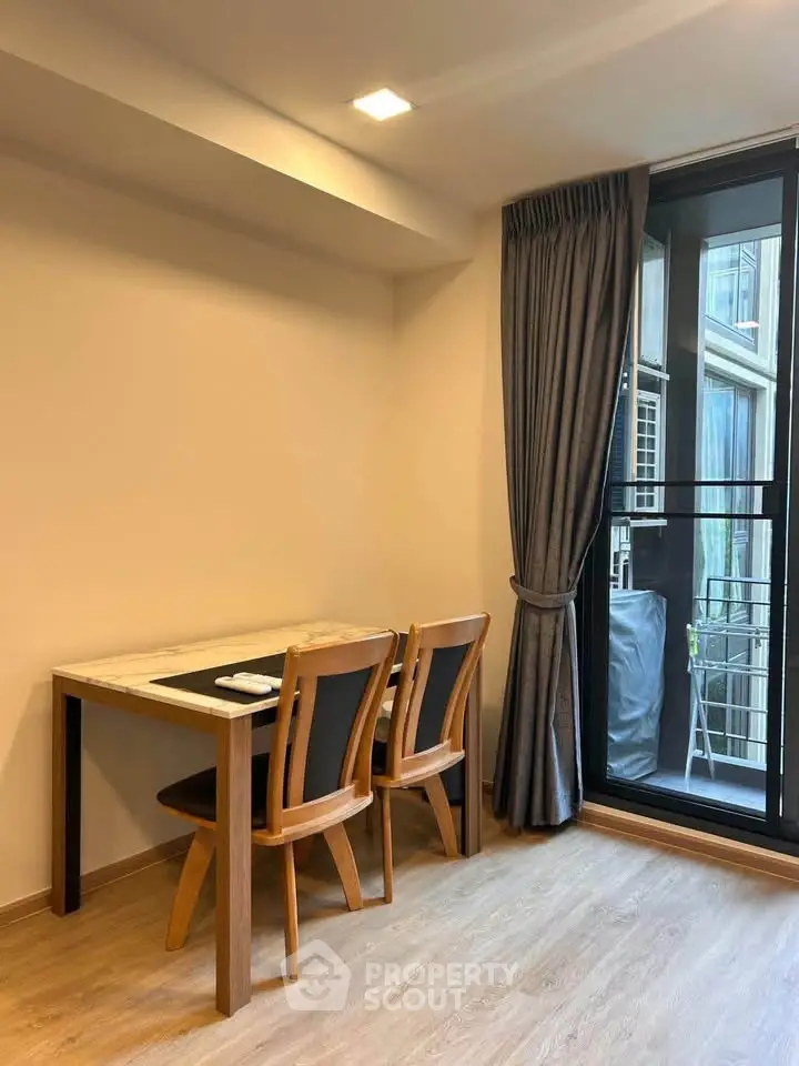 Modern dining area with wooden table and chairs next to a large window with curtains.