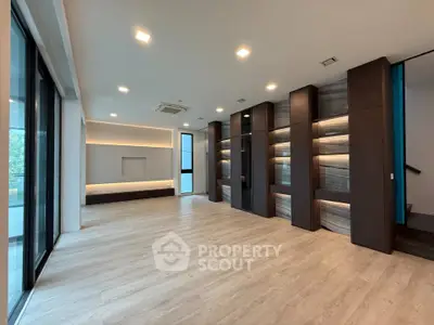 Spacious modern living room with sleek wooden flooring and built-in shelving, perfect for stylish urban living.