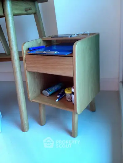 Modern wooden bedside table with drawer and open shelf in stylish bedroom.