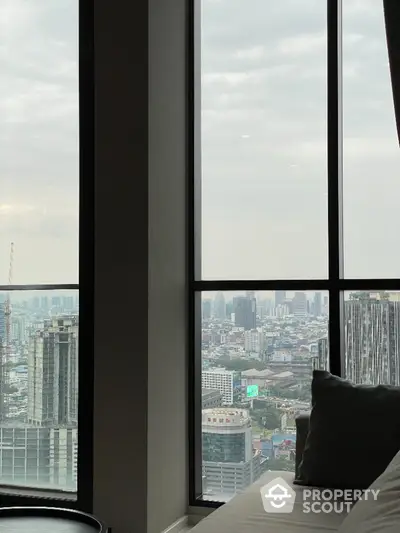 Luxurious high-rise bedroom with floor-to-ceiling windows offering a panoramic cityscape view, embodying urban elegance and modern comfort.