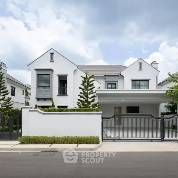 Elegant modern white house with gated entrance and lush landscaping.