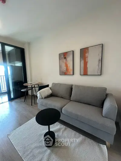 Modern living room with gray sofa, abstract art, and balcony view