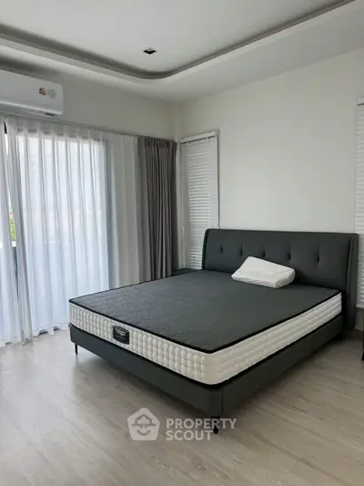 Spacious bedroom with modern decor and large windows for natural light.