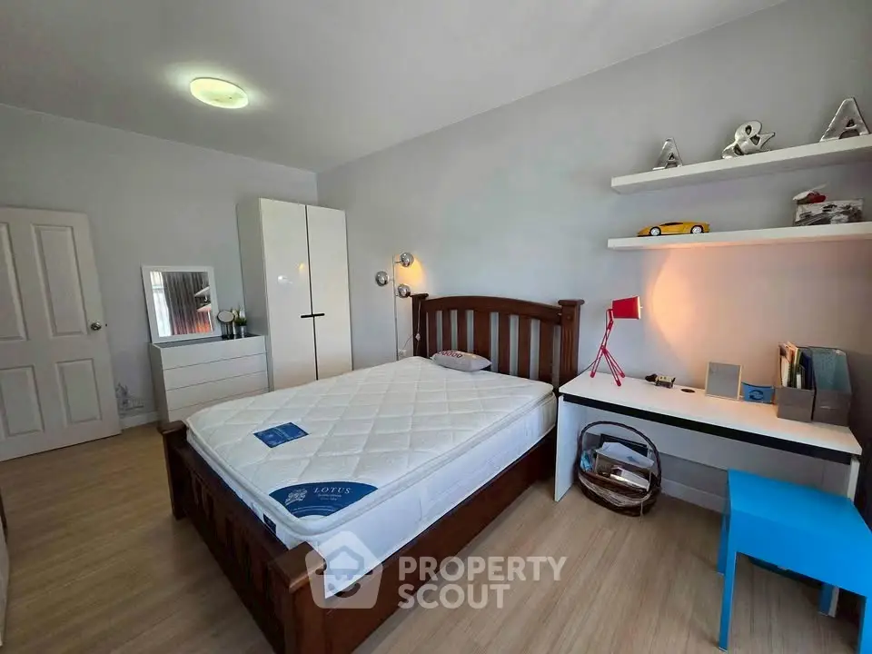 Cozy bedroom with wooden bed frame, study desk, and modern decor in a bright, inviting space.