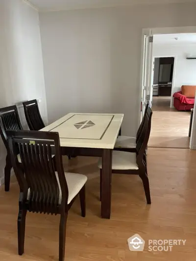 Spacious dining area with elegant wooden table set, seamlessly connected to a cozy living room with ample natural light, perfect for family gatherings.