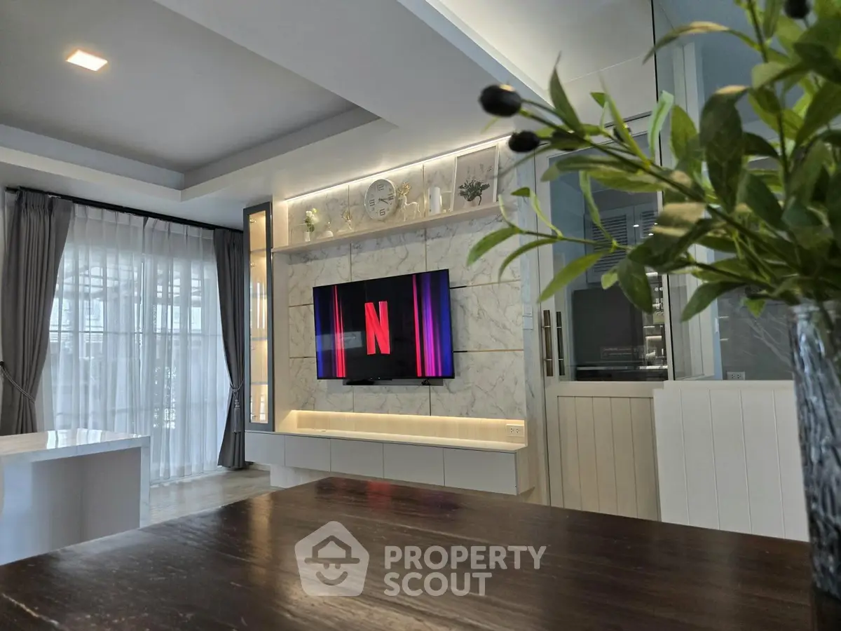 Modern living room with stylish decor and large TV, perfect for entertainment and relaxation.