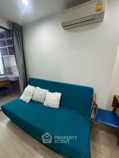Cozy living room with teal sofa and air conditioning in modern apartment.