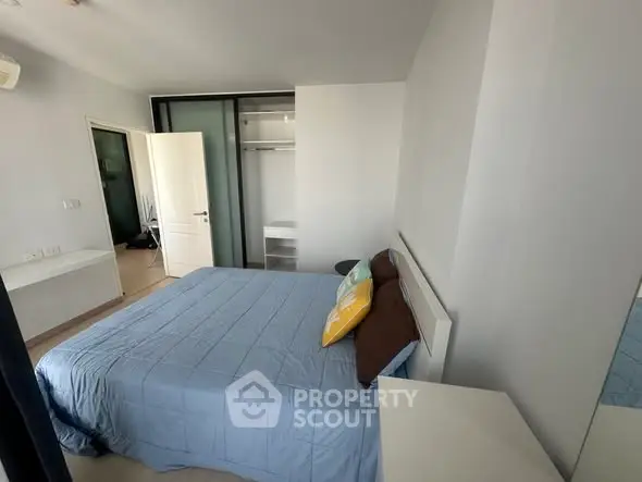 Modern bedroom with blue bedding and open closet in a bright apartment.