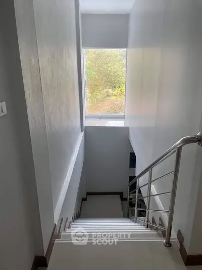 Modern staircase with large window offering natural light and outdoor view.
