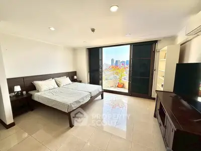 Spacious bedroom with city view and modern furnishings in a high-rise apartment.
