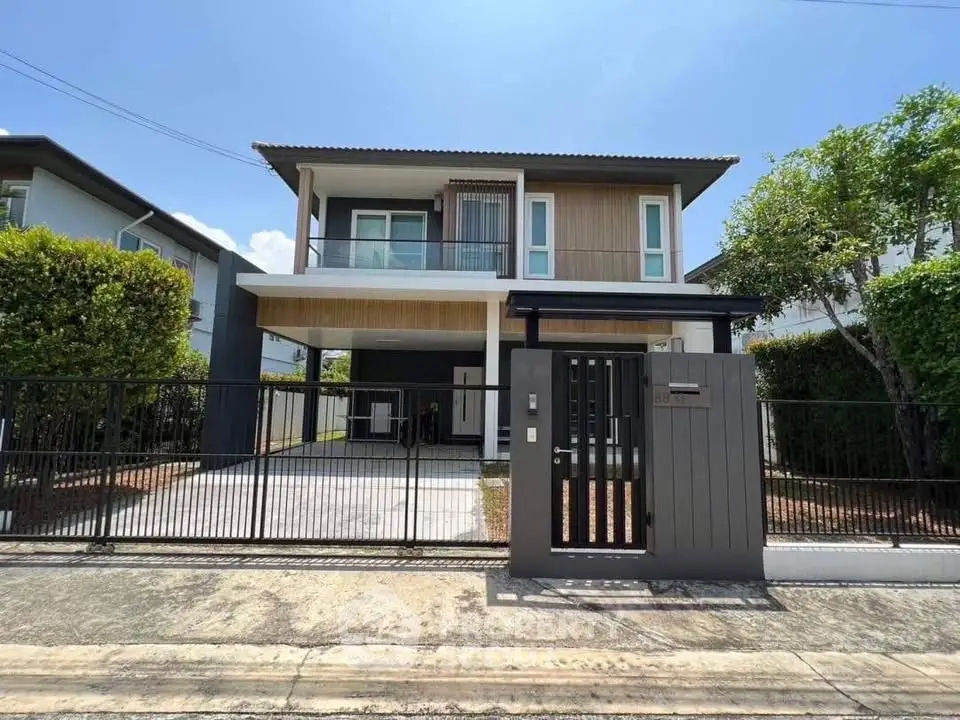 Modern two-story house with gated entrance and driveway in a suburban neighborhood.