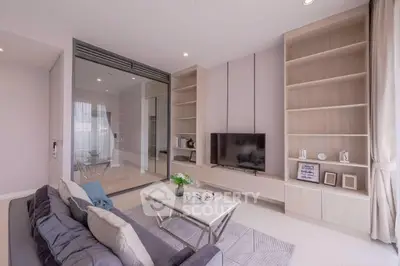 Modern living room with sleek built-in shelves and large TV, featuring elegant decor and ample natural light.
