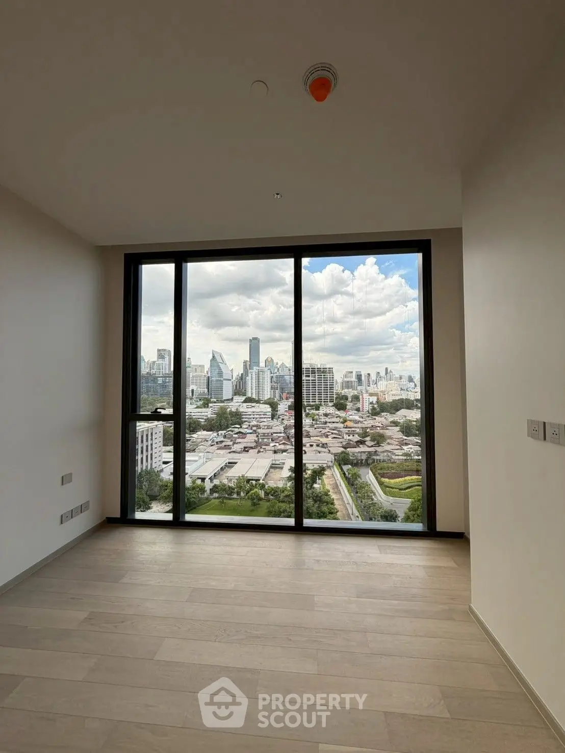 Spacious room with floor-to-ceiling windows offering stunning city skyline views.