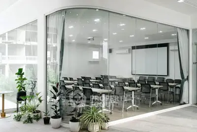 Modern office space with glass walls and stylish furniture, ideal for meetings and conferences.