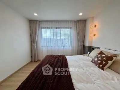 Cozy bedroom with elegant decor and large window offering natural light.