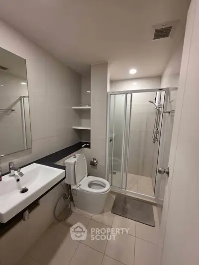 Modern bathroom with shower, toilet, and sink in sleek design.