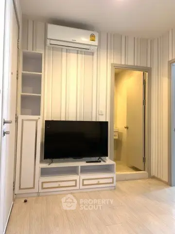 Modern living room with TV and air conditioning, featuring stylish striped wallpaper and light wood flooring.