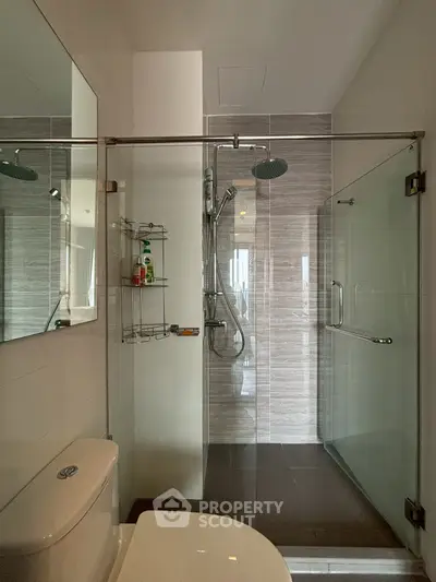 Modern bathroom with glass shower enclosure and sleek fixtures in a contemporary apartment.