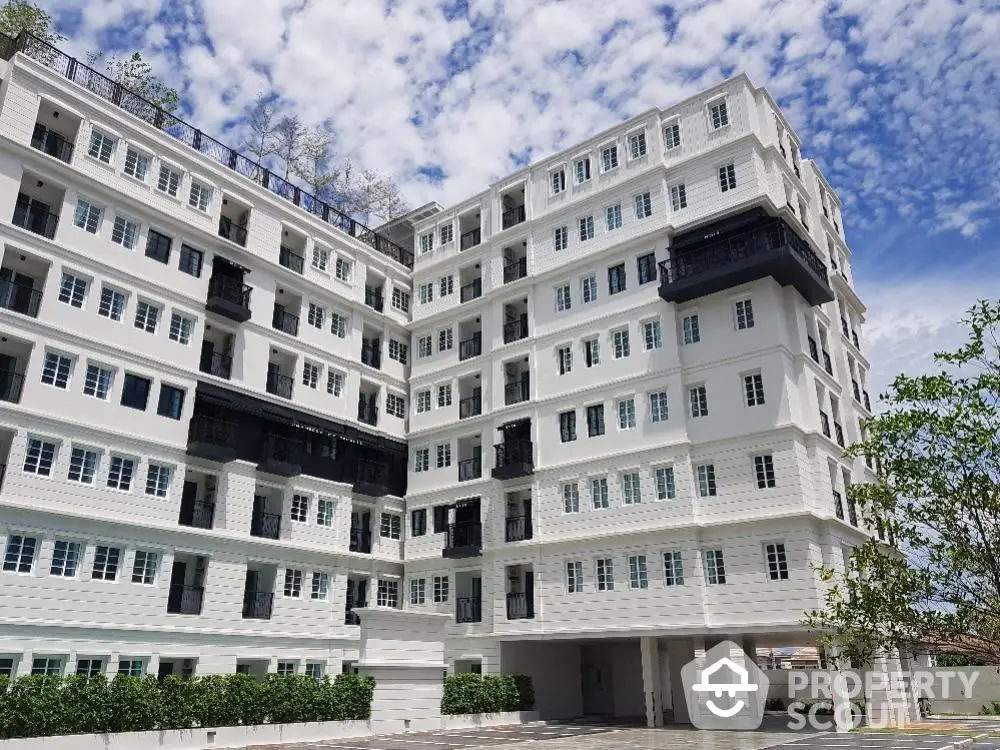 Majestic multi-story residential building with ample parking and modern architectural design, set against a clear blue sky, offering luxurious urban living spaces.