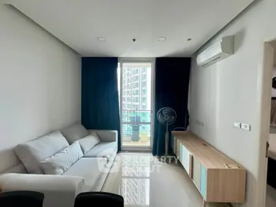 Modern living room with sleek furniture and balcony view in a high-rise apartment.