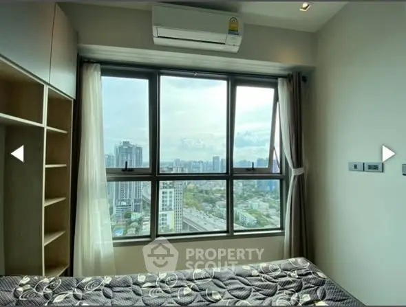 Modern bedroom with large window offering stunning city view, featuring air conditioning and stylish decor.