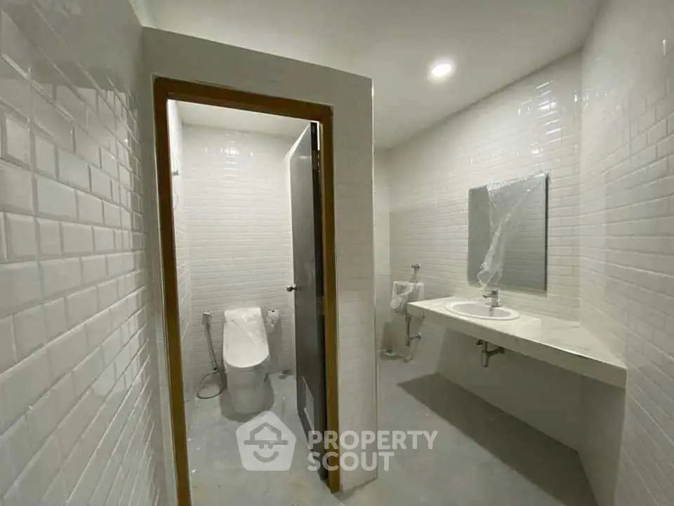 Modern bathroom with sleek white tiles and contemporary fixtures.