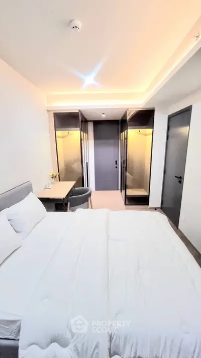 Modern bedroom with elegant lighting and cozy bedding in a stylish apartment.