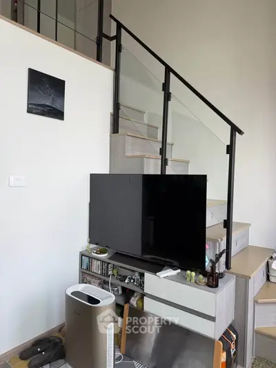 Modern living room with stylish staircase and sleek TV setup