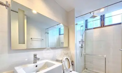 Modern bathroom with sleek fixtures and large mirror in a bright, airy space.