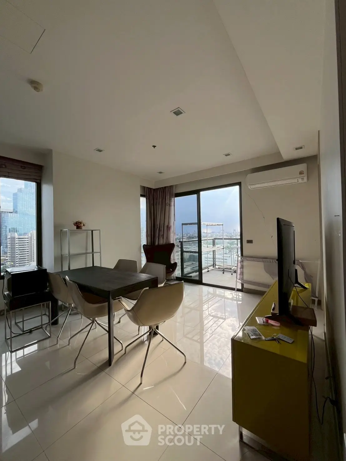 Modern living room with city view and balcony access, featuring sleek furniture and ample natural light.