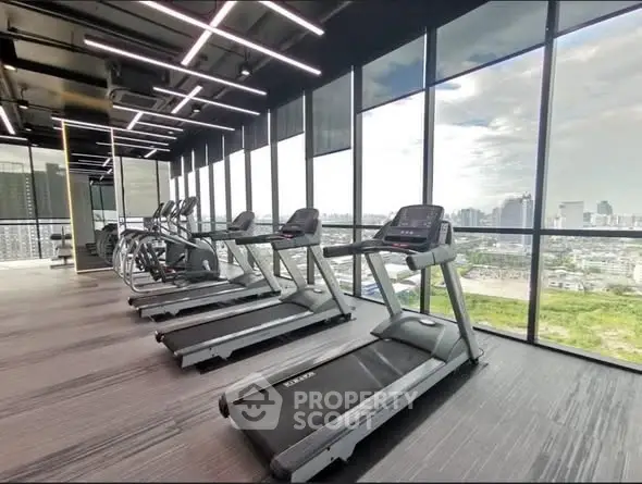 Modern gym with treadmills and panoramic city view in luxury building.