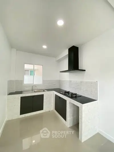 Modern kitchen with sleek black cabinets and gas stove in a bright, minimalist design.