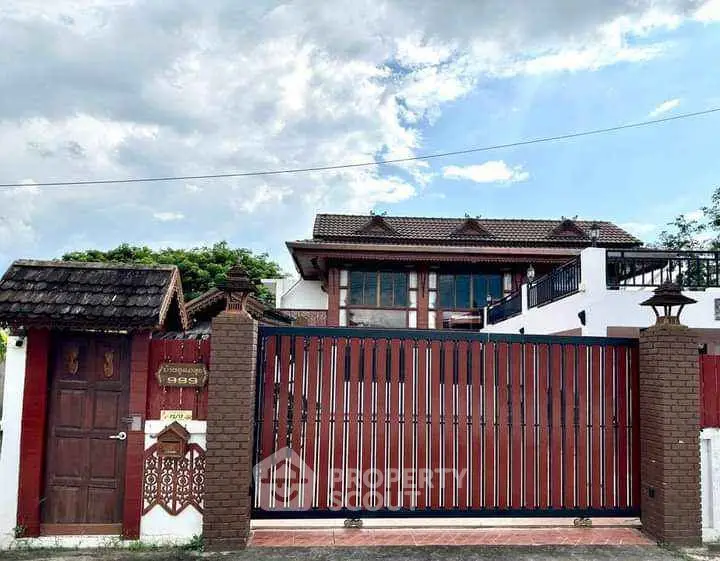 Charming traditional-style house with wooden gate and lush greenery, perfect for serene living.