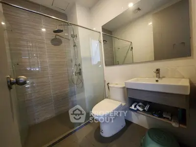 Modern bathroom with glass shower, sleek sink, and toilet in contemporary apartment.