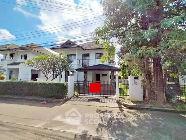 Charming two-story house with gated entrance and lush greenery in a serene neighborhood.