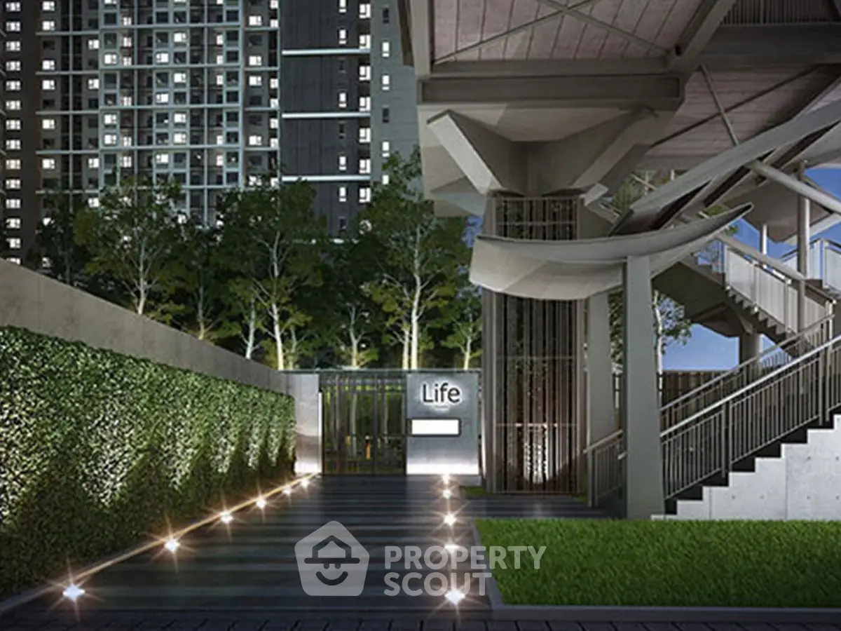 Modern urban entrance with sleek architecture and lush greenery at a high-rise building.