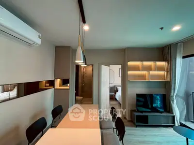 Modern open-plan living room with dining area and view into bedroom, featuring sleek furniture and ambient lighting.