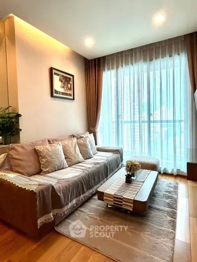 Elegant living room with large windows and cozy seating area in modern apartment.