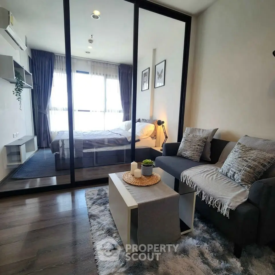 Modern living room with cozy decor and glass partition leading to bedroom