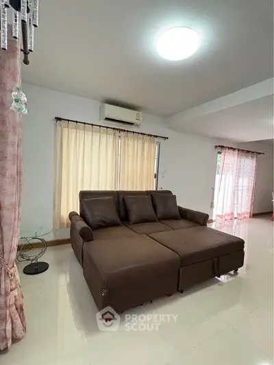Spacious living room with modern brown sofa and natural light