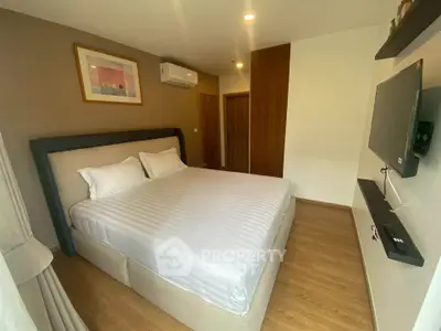 Modern bedroom with cozy bed, wall-mounted TV, and stylish decor in a contemporary apartment.