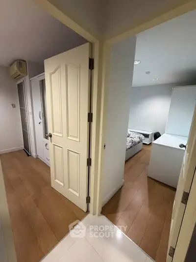 Spacious apartment hallway leading to two cozy bedrooms with wooden flooring and modern decor.