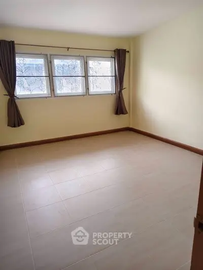 Spacious empty room with tiled floor and large windows, perfect for customization.