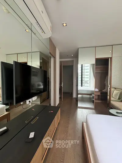 Modern bedroom with mirrored walls and sleek furniture in a high-rise apartment.
