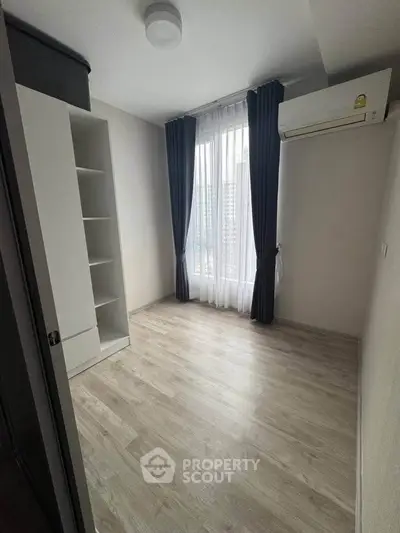 Spacious bedroom with modern flooring and large window offering city views, perfect for urban living.